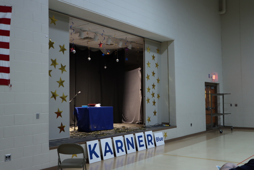 A stage in a gym decorated in stars with the sign that says Karner Blue below it. 