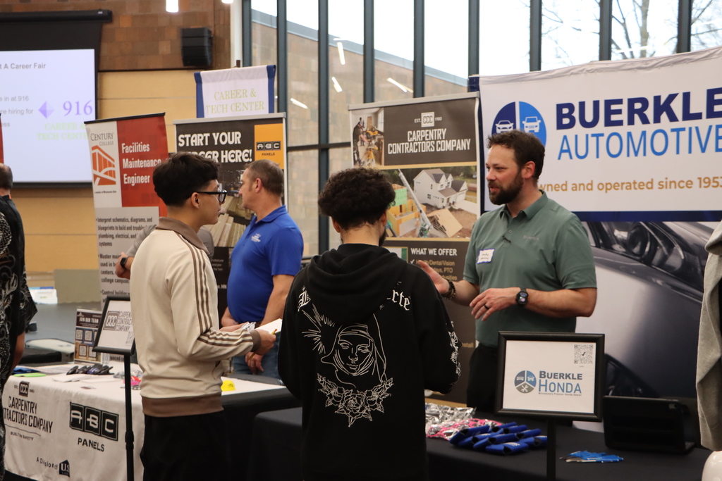 Two students talking to an industry professional. 