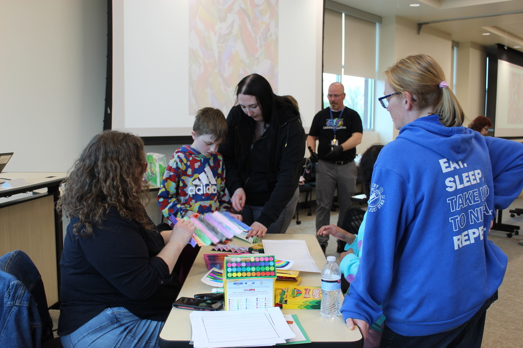 Staff, students, and families doing an art activity at a table.