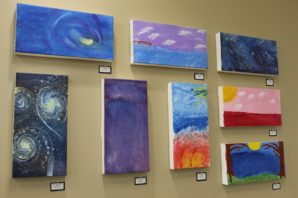 A wall of various paintings made from students.