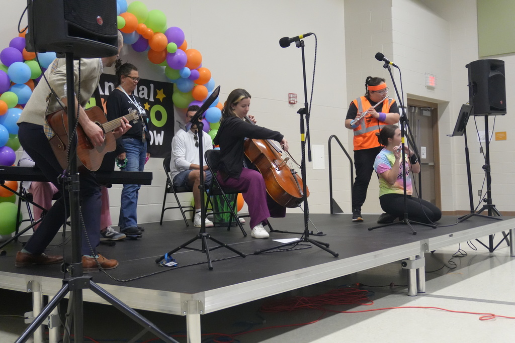 A group of staff playing instruments on stage for the talent show.