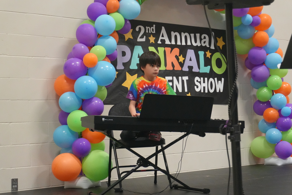 A student playing the keyboard piano on stage.