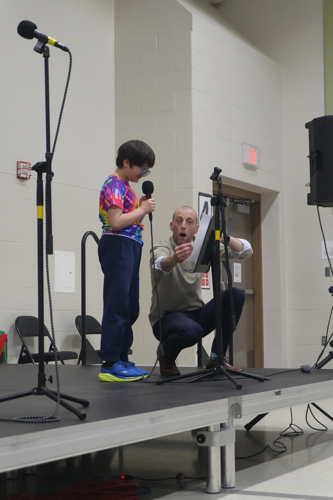 A staff helping out a student that is performing on stage for the talent show.