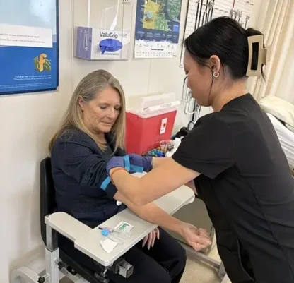 A Phlebotomy student putting a tourniquet on Superintendent Val Rae Boe.