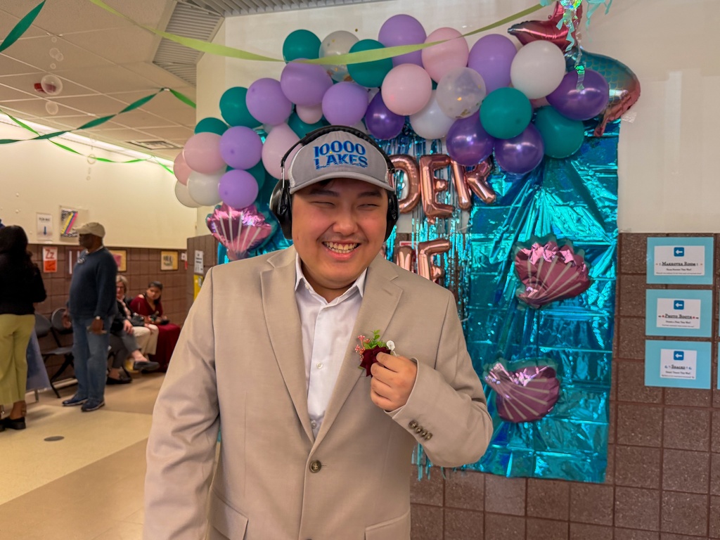 Student smiling for camera in front of the "Under the Sea" theme backdrop.