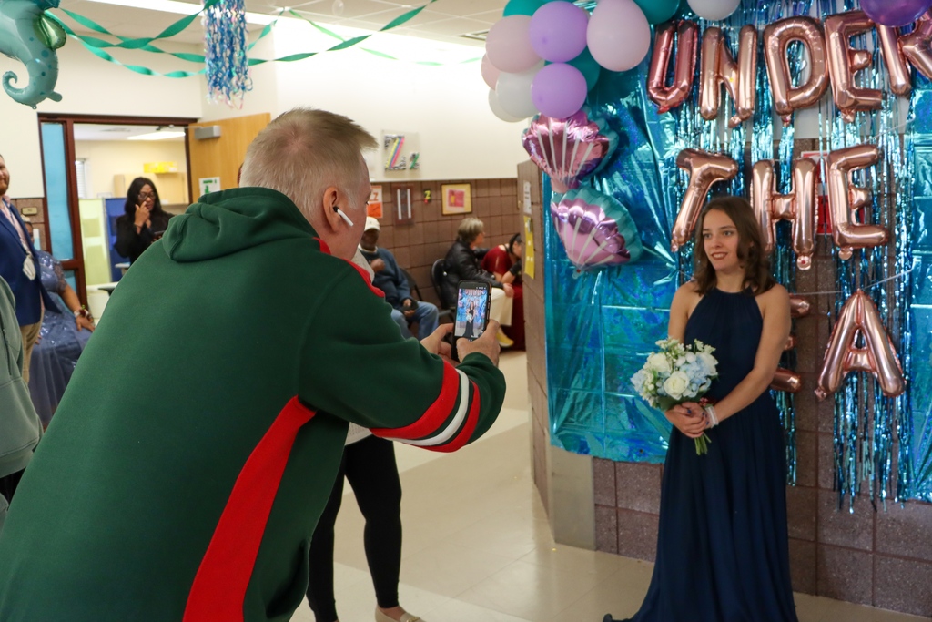 Parent taking a picture of a student in front of the "Under the Sea" theme.