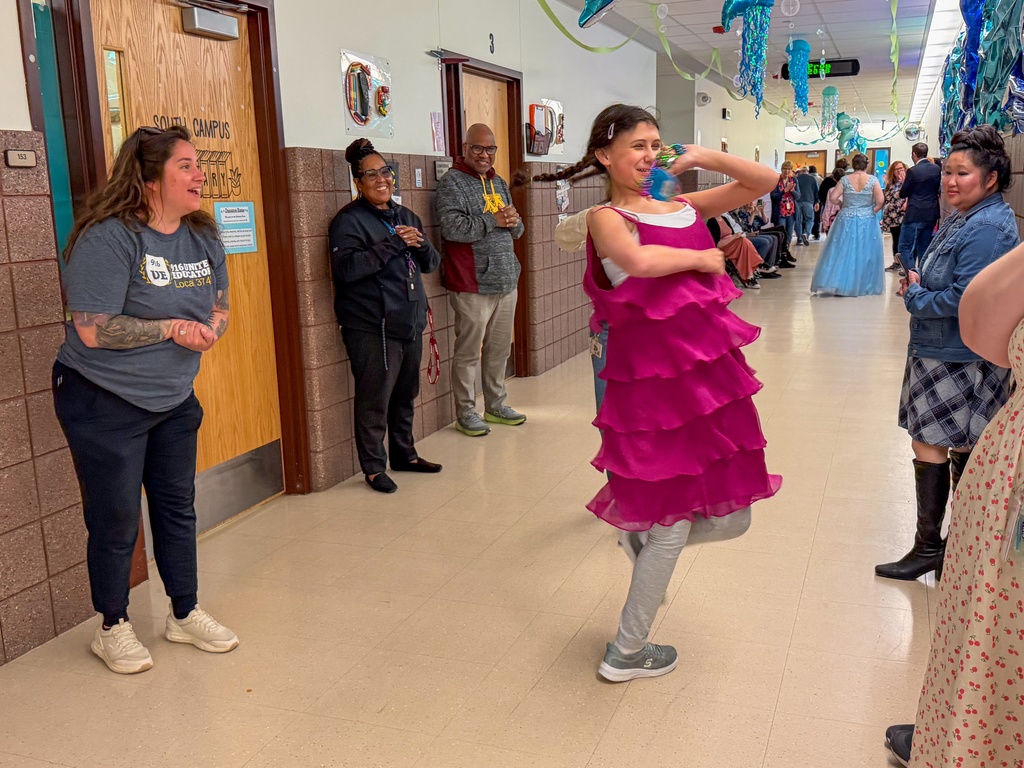 Student twirling around in front of staff and family.