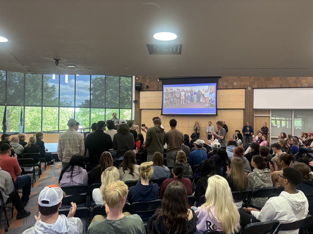 Students and staff at a end of year assembly and celebrating.