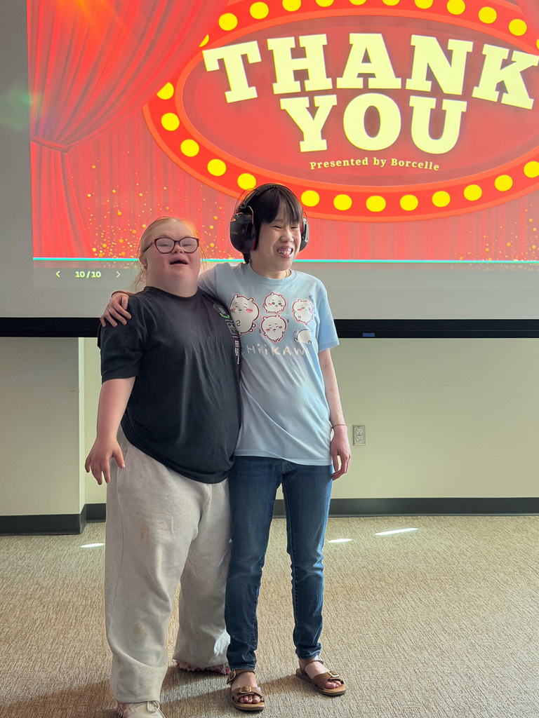 Two students smiling with arms around each other.