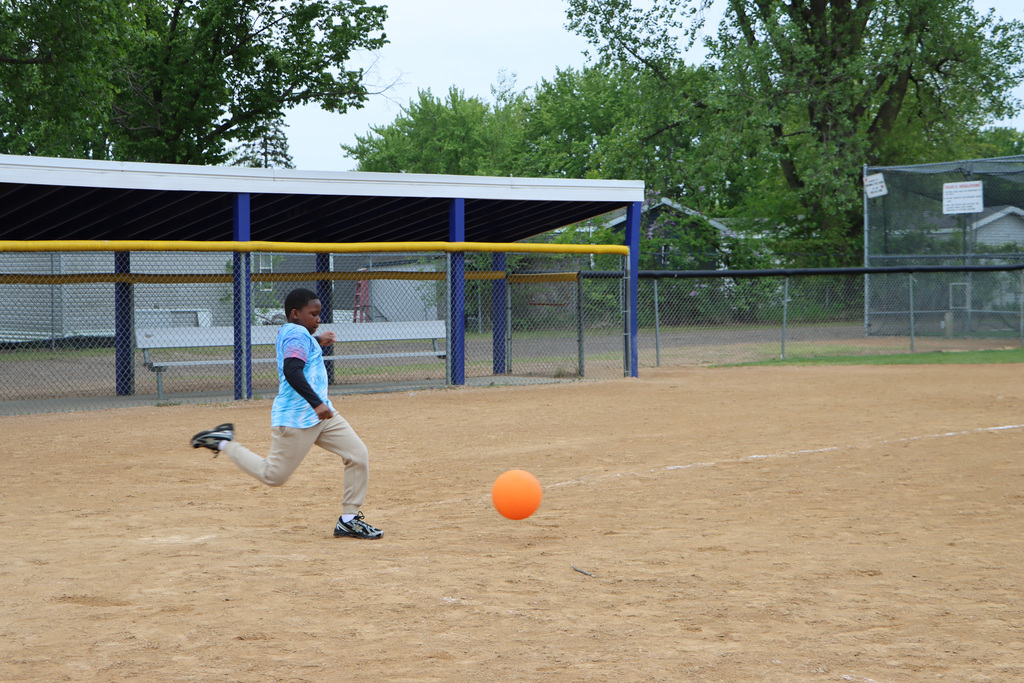 Student moving in motion to kick the kickball.