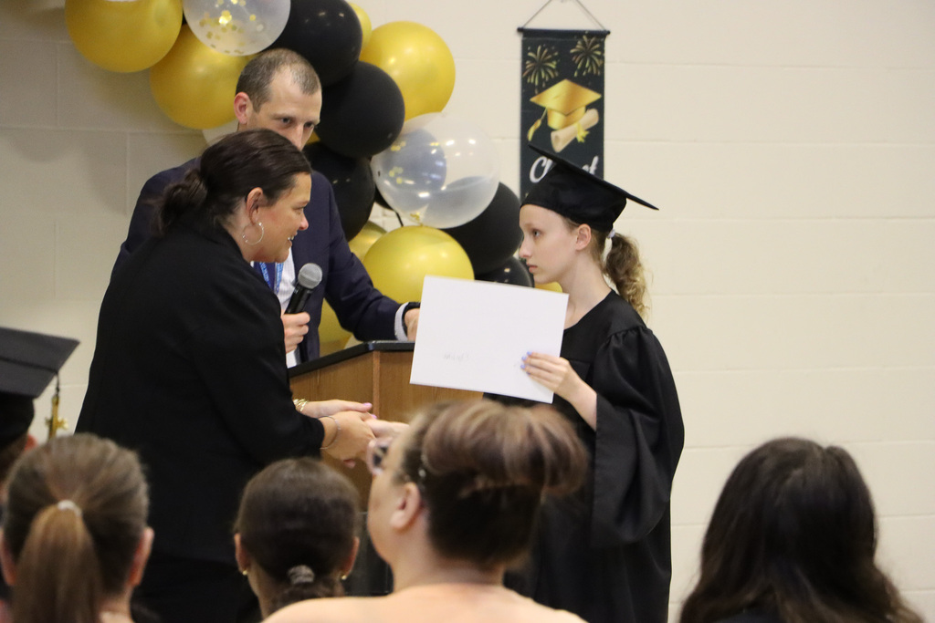 Principals congratulating the student on graduating with a certificate. 