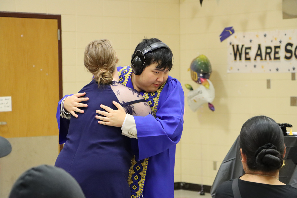 Student hugging student graduate in celebration.