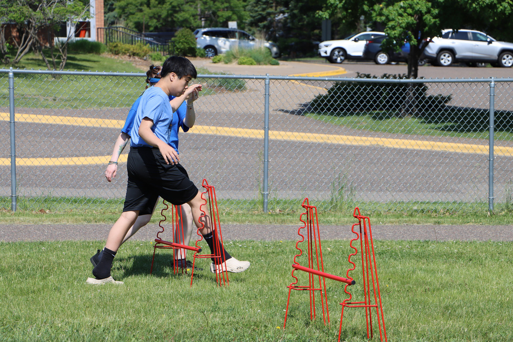 Staff leading student through the hurdles. 