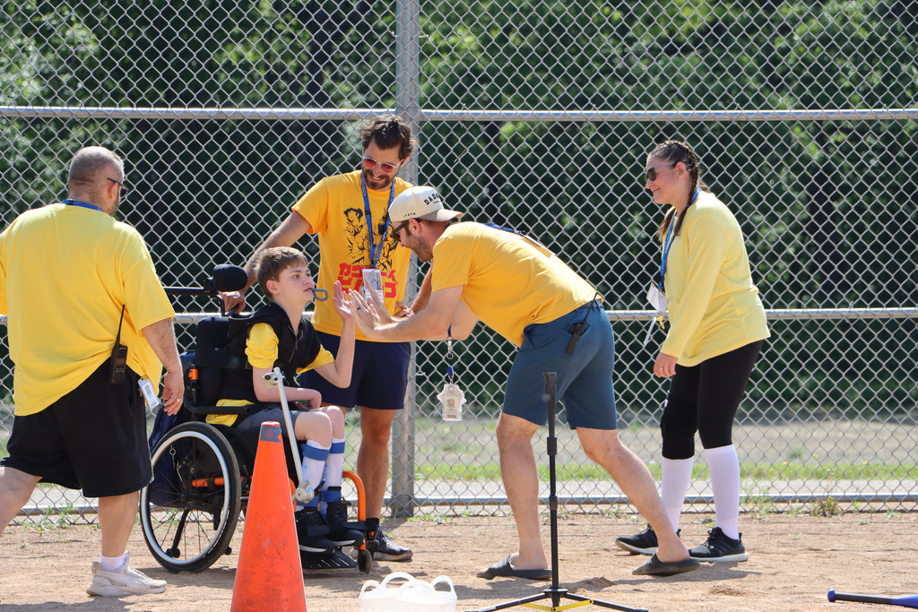 Staff giving a high five to student while they are playing T-ball.