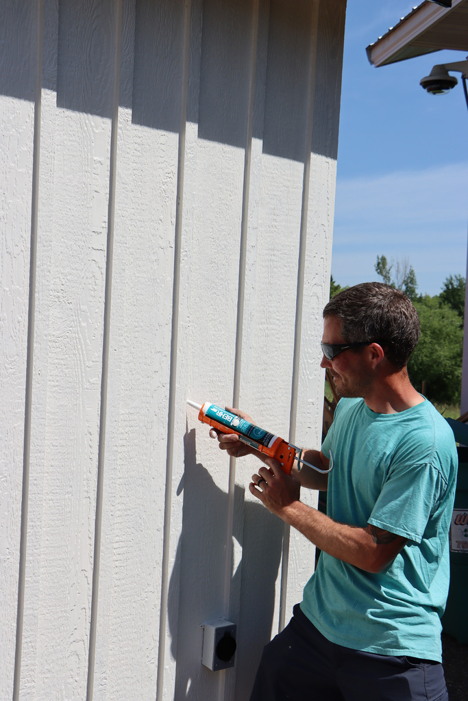Teacher caulking the outside of the student built sauna.