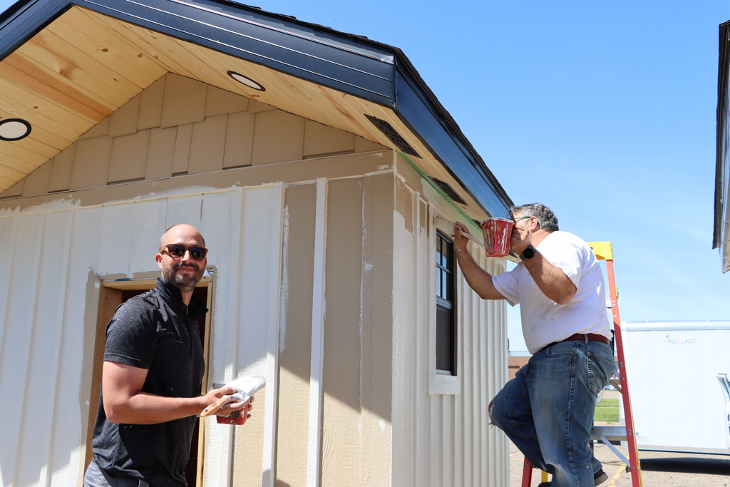 Two staff painting the student built sauna. 