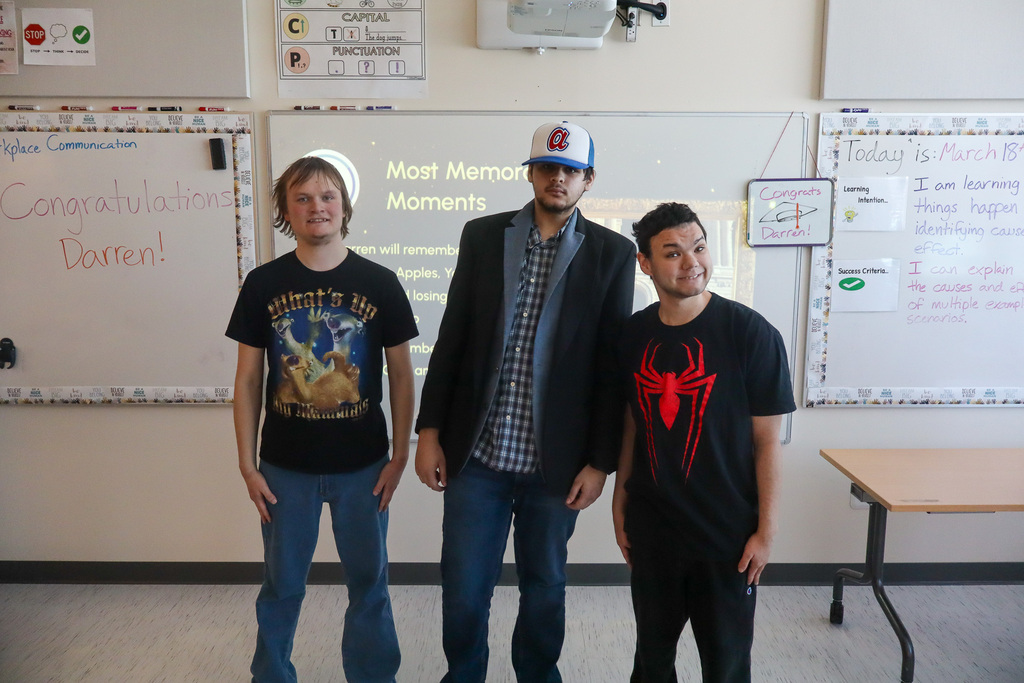 Three students taking a picture together in celebration of the student graduate. 