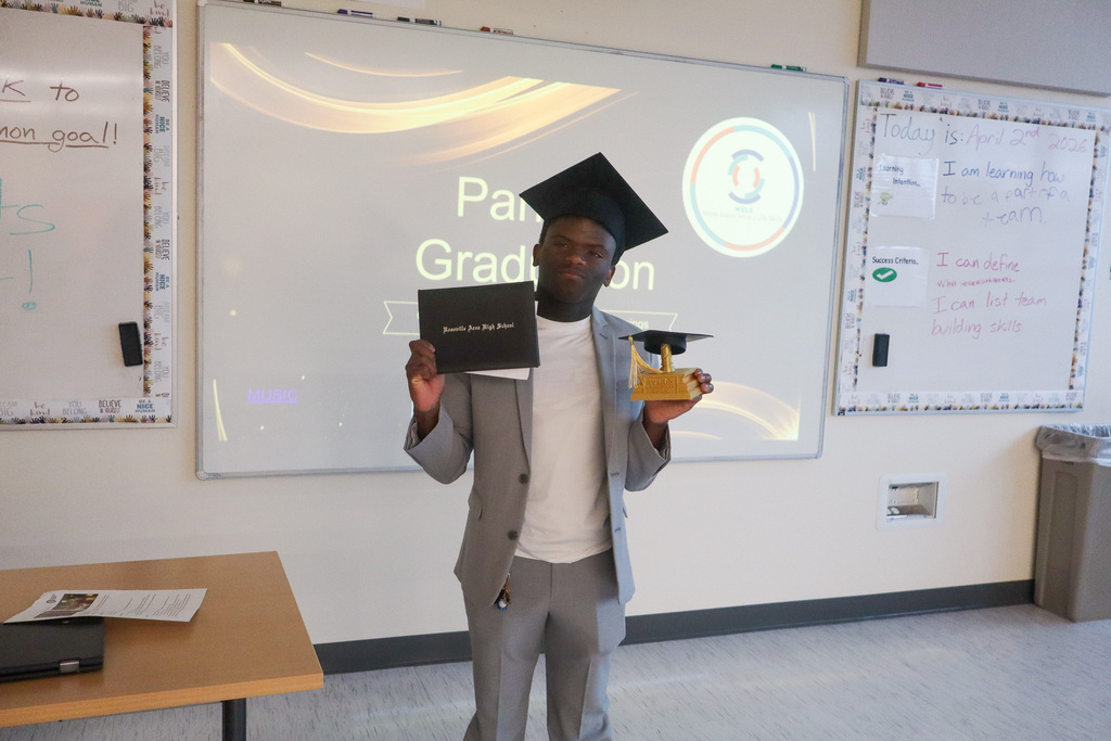Student graduate holding a diploma and smiling for the picture. 
