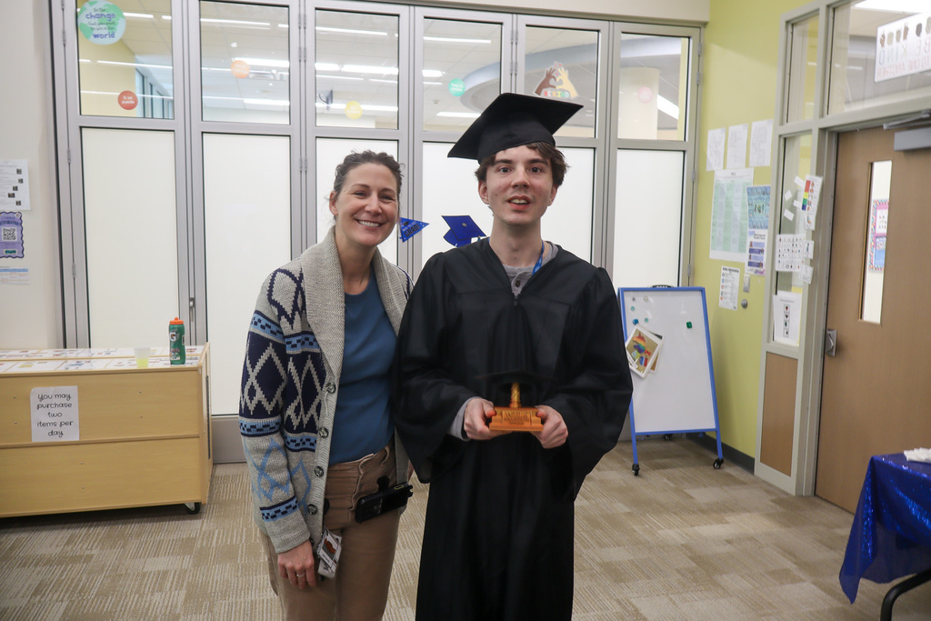 Staff and student graduate smiling while taking a photo. 