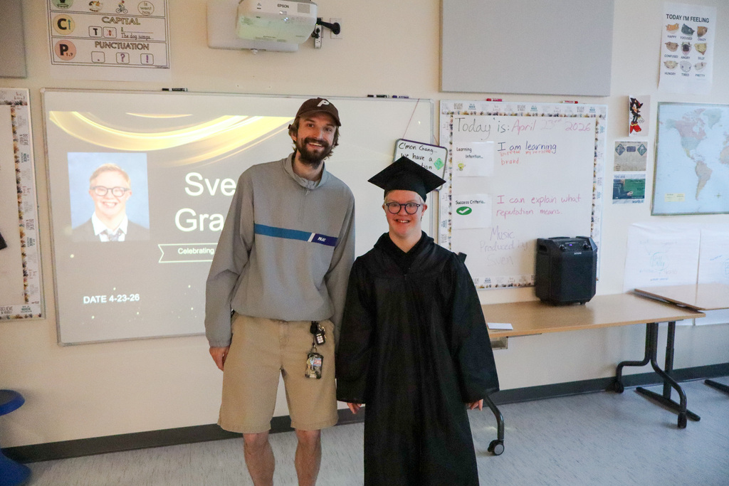 Staff and student smiling and taking a picture together in celebration of the student graduating. 