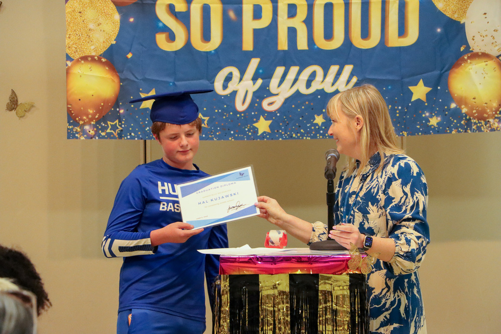 Principal handing student a certificate during graduation ceremony.