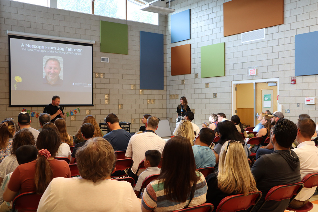 Students, staff, and families watching principal give speech. 