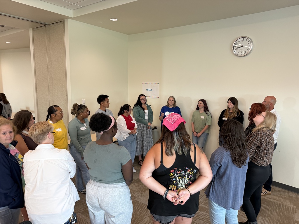 Staff gathered in a circle and talking with each other. 