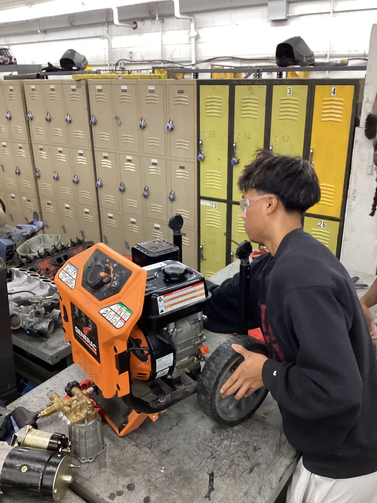 Student in a workshop classroom working on an engine.