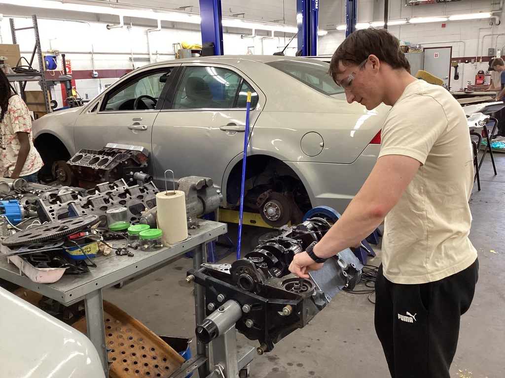 Student in a workshop classroom working on an engine.