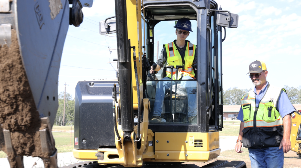 Instructor Craig Cooper, right, instructs a student on a piece of heavy machinery.