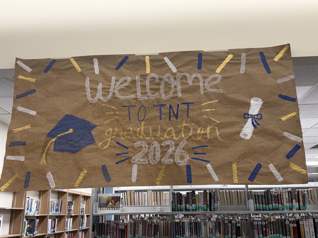 A banner in a library reads "Welcome to TNT Graduation 2026". The banner has a graduation cap, tassel, and diploma symbols.