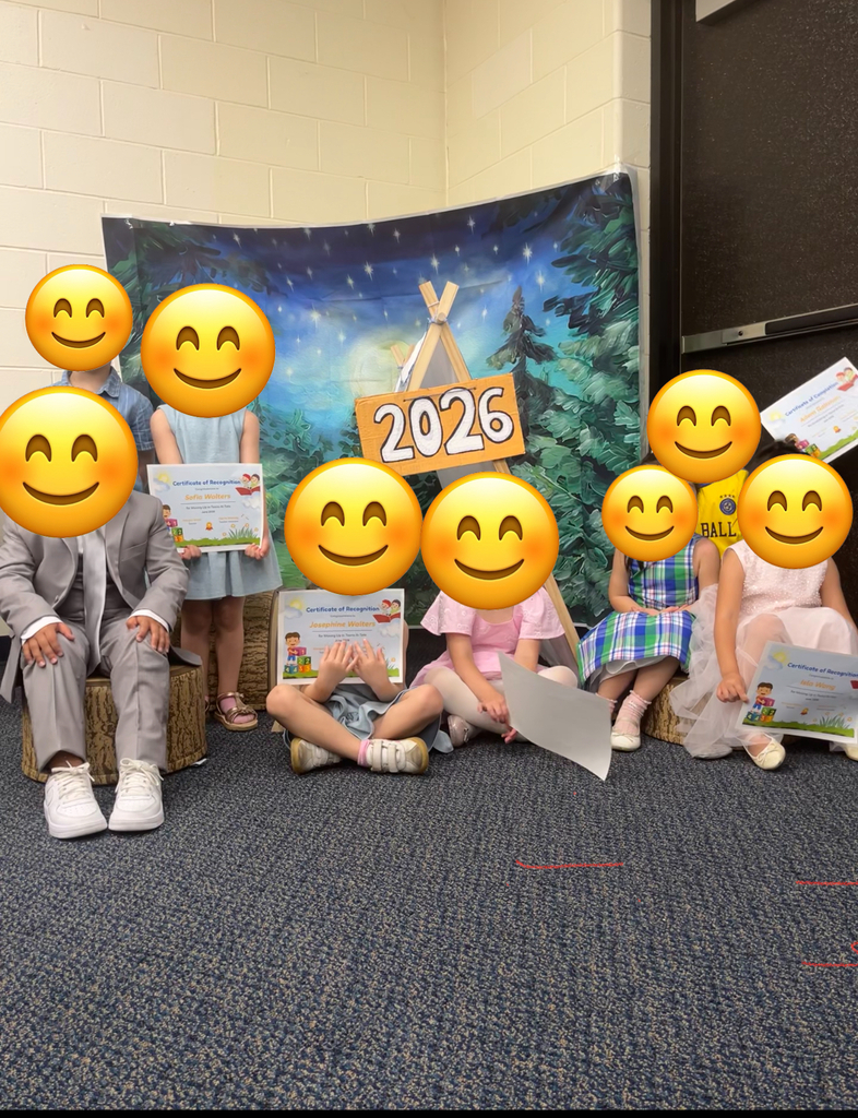 A group of children sitting in front of a banner, all wearing smiley face overlays.