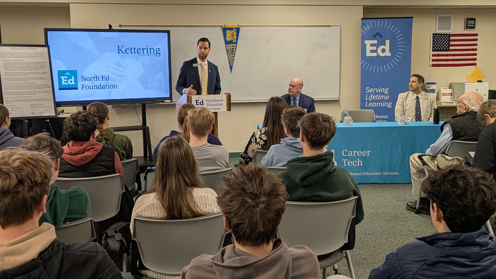 A man speaks from a podium to a room full of people.