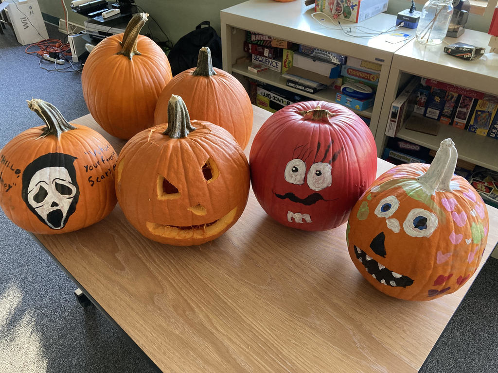 Image of six pumpkins with various painted faces and designs.