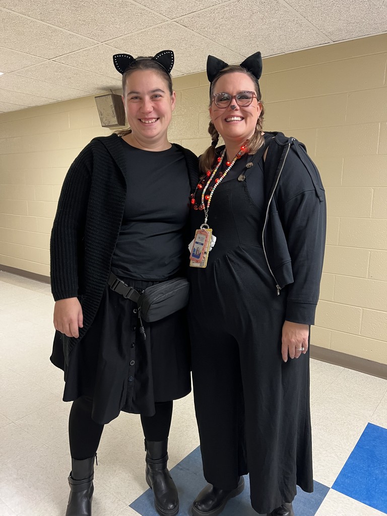 Two Bridgeway staff members posing in the hallway, dressed as black cats.