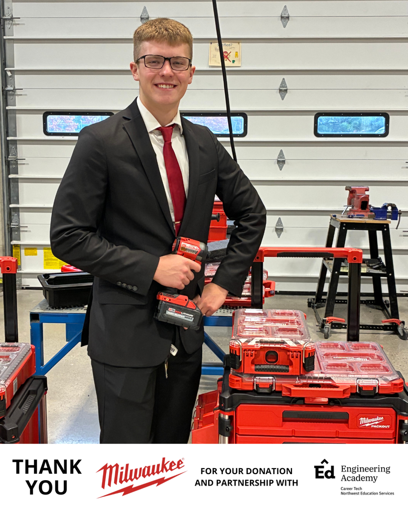 A single student dressed in a black suit and red tie poses proudly while holding a Milwaukee cordless drill. Behind him are stacked red Milwaukee Packout toolboxes on metal shelves. The bottom of the image contains a white banner with the Milwaukee logo and Engineering Academy logo, and text reading “THANK YOU FOR YOUR DONATION AND PARTNERSHIP WITH Ed Engineering Academy.” The setting appears to be an industrial workshop or classroom.