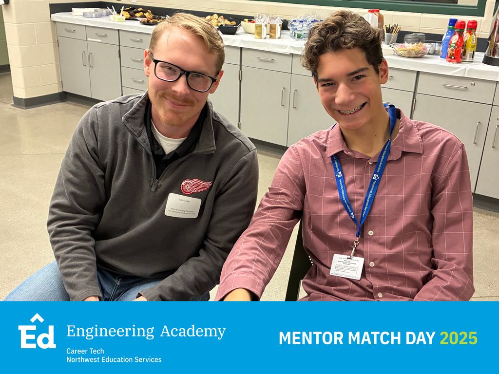 A close-up, seated portrait of an adult male mentor wearing a gray sweatshirt and glasses, and a teenage boy with braces wearing a pink/maroon patterned button-up shirt and an ID lanyard. They are smiling and sitting in a classroom with classroom-style cabinets and a buffet of food in the background. The bottom of the image has a blue banner with the Northwest Education Services Career Tech Engineering Academy logo and white text: "MENTOR MATCH DAY 2025.”