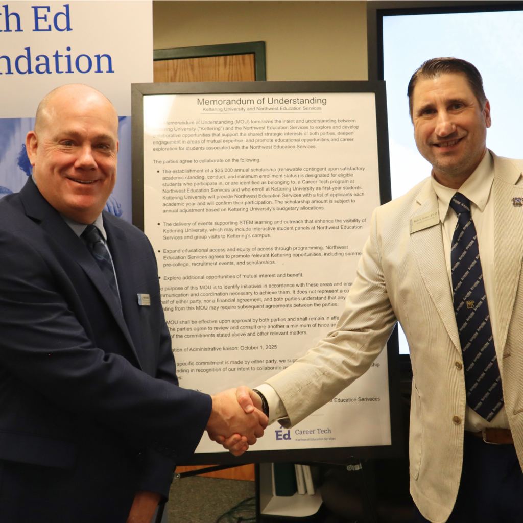 Pat Lamb and Dr. Rob Kniss posing while shaking hands in front of Memorandum of Understanding.