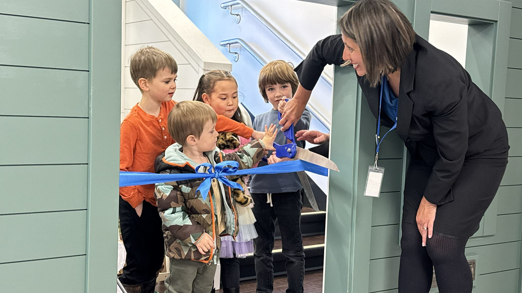 Yvonne Donohoe McCool cutting a ceremonial ribbon with four children under the age of 6 to celebrate the new Joseph C. Fischer Early Childhood and Family Center.