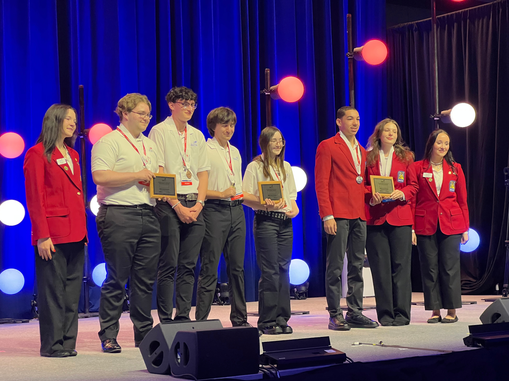 Four Career Tech Film & New Media students wearing white polos and black pants on stage with several other award recipients at the 2026 SkillsUSA Michigan