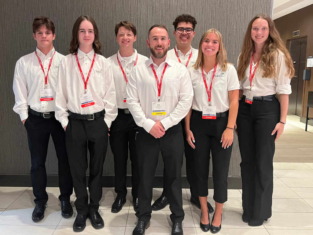 North Ed Career Tech Aviation Maintenance students and instructor wearing white shirts, black pants and red lanyards, smiling and posing at 2026 SkillsUSA Michigan. 