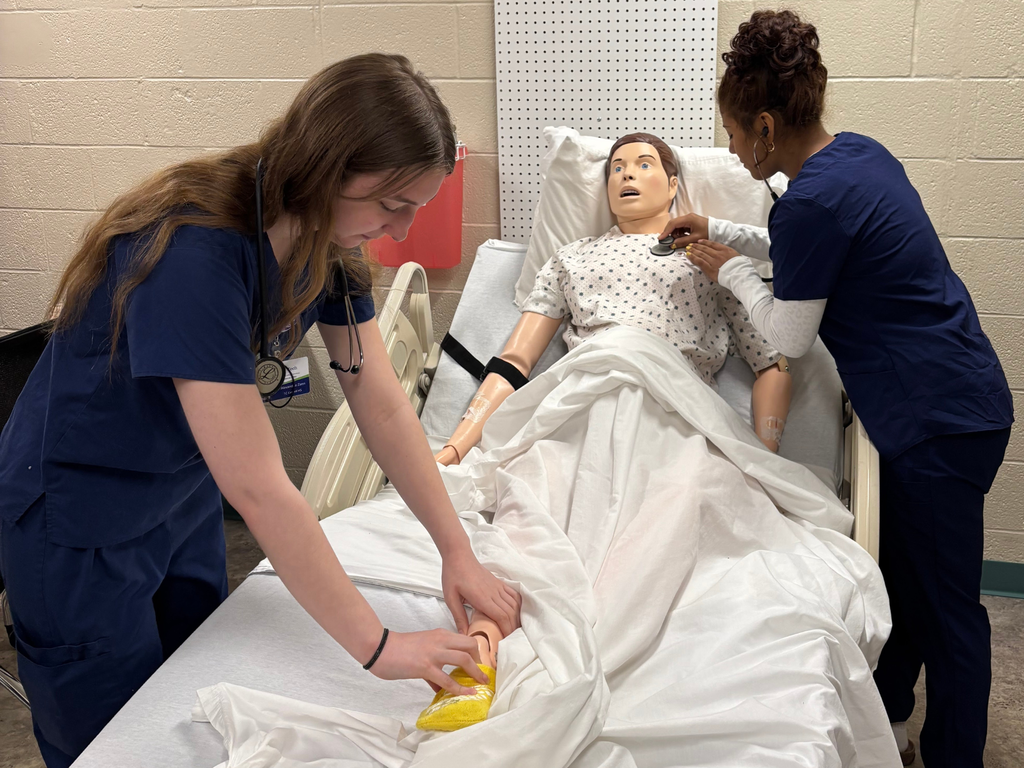 Two Career Tech Health Sciences students practicing evaluating a manikin placed in a hospital bed. 