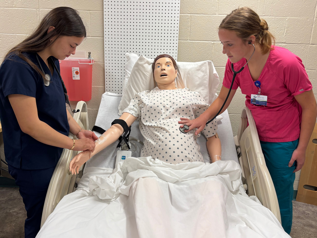 Two Career Tech Health Sciences students practicing evaluating a manikin placed in a hospital bed. 