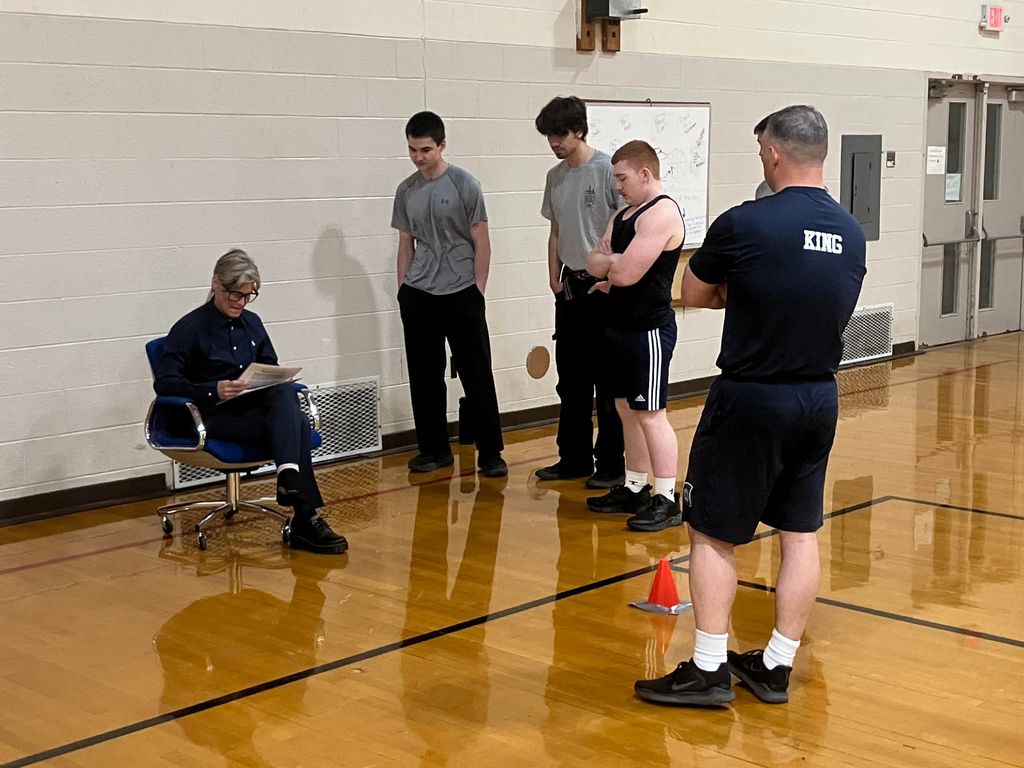 Public Safety students standing in a gymnasium awaiting the MCOLES Fitness Exit exam results from the test proctor. 