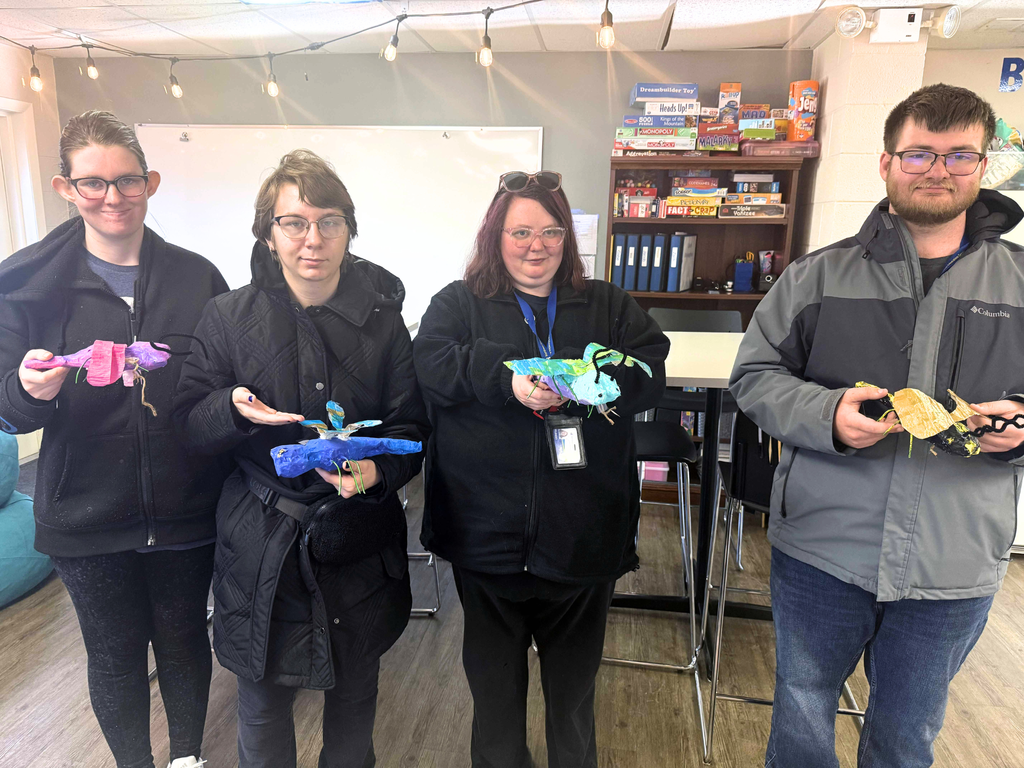 Photo: Four ACE students holding their paper mache insect creations. 