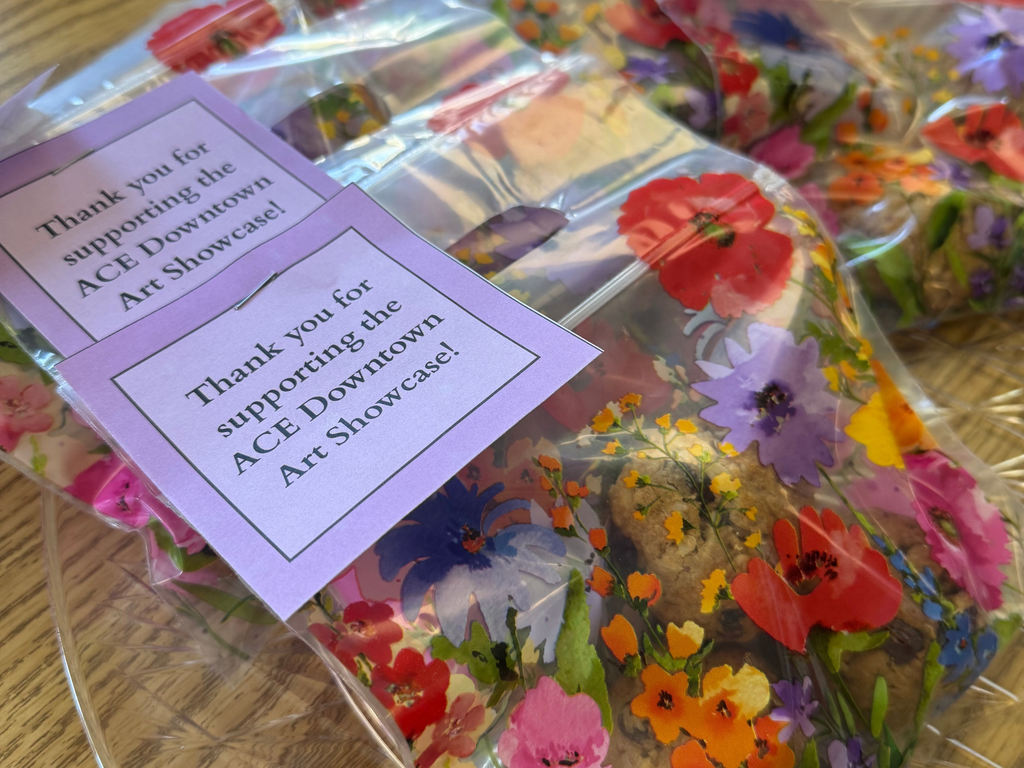 Photo: Close up of floral plastic baggies filled with baked goods and tags reading “Thank you for supporting the ACE Downtown Art Showcase!”