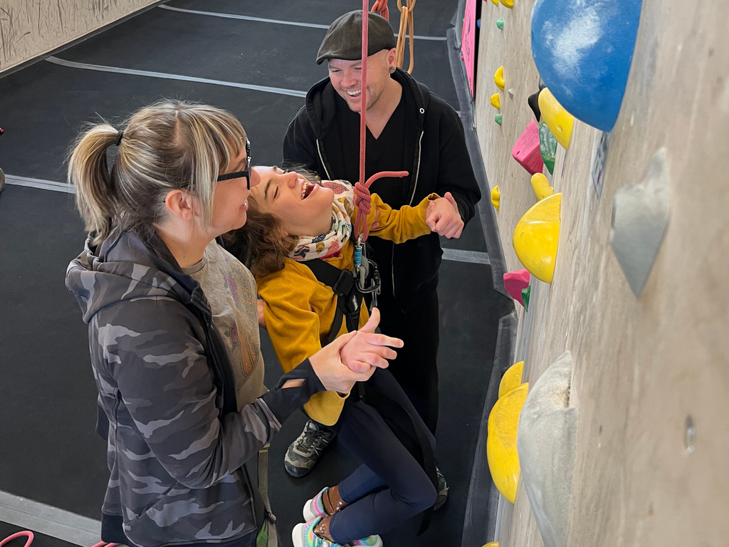 Two adults helping a North Ed student rock climb at Ele8. 