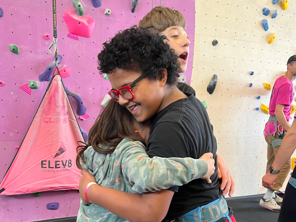 Two students hugging happily at Elev8 rock climbing gym. 