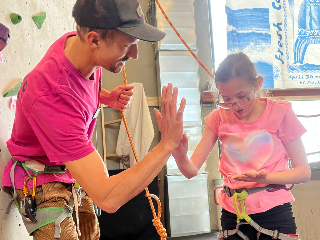 Student giving an adult a high-five at Elev8 rock climbing gym. 