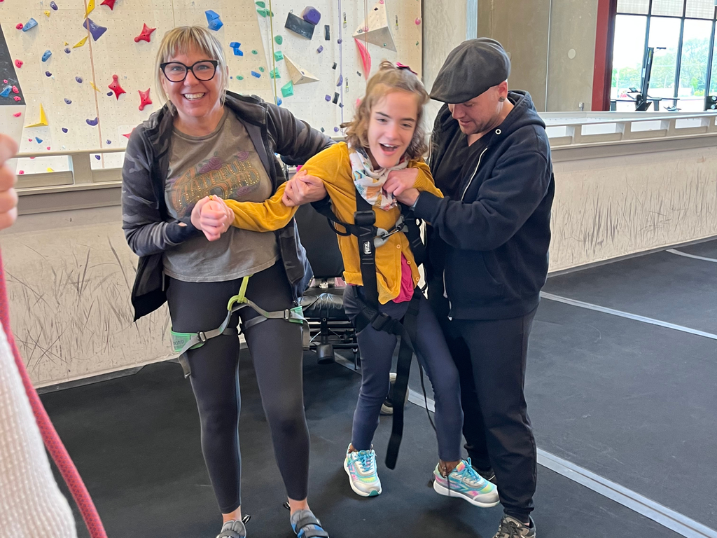 Two adults holding and supporting student at Elev8 rock climbing gym. 